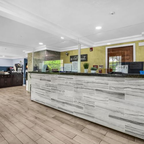 A modern hotel lobby with a long marble reception desk, Wi‑Fi sign, and a &ldquo;WELCOME&rdquo; wall banner.